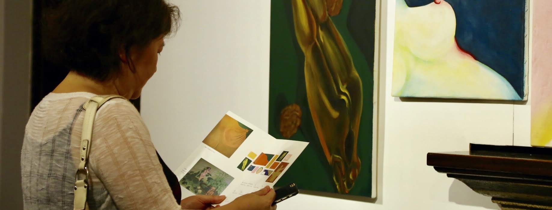 A woman looking at the catalogue in front of the artwork